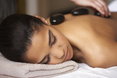 A woman relaxes to a warm, calming hot stone massage.